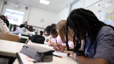 Schüler sitzen während des Unterrichts nebeneinander in einer Klasse und schreiben.