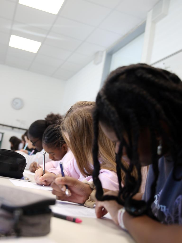 Schüler sitzen während des Unterrichts nebeneinander in einer Klasse und schreiben.