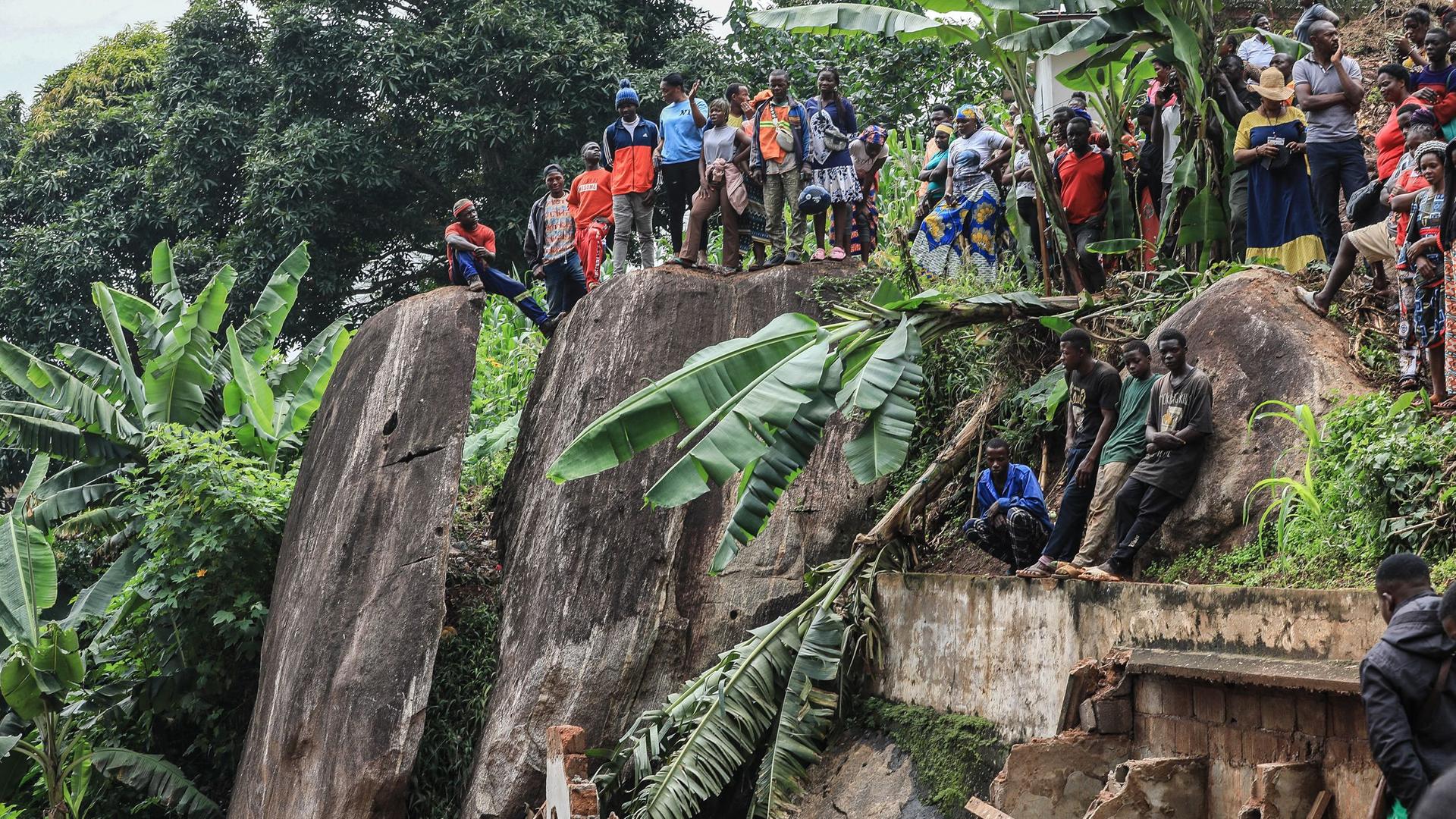 Menschen stehen auf einem Felsen und schauen herunter auf den eingestürzten Staudamm bei Jaunde in Kamerun.