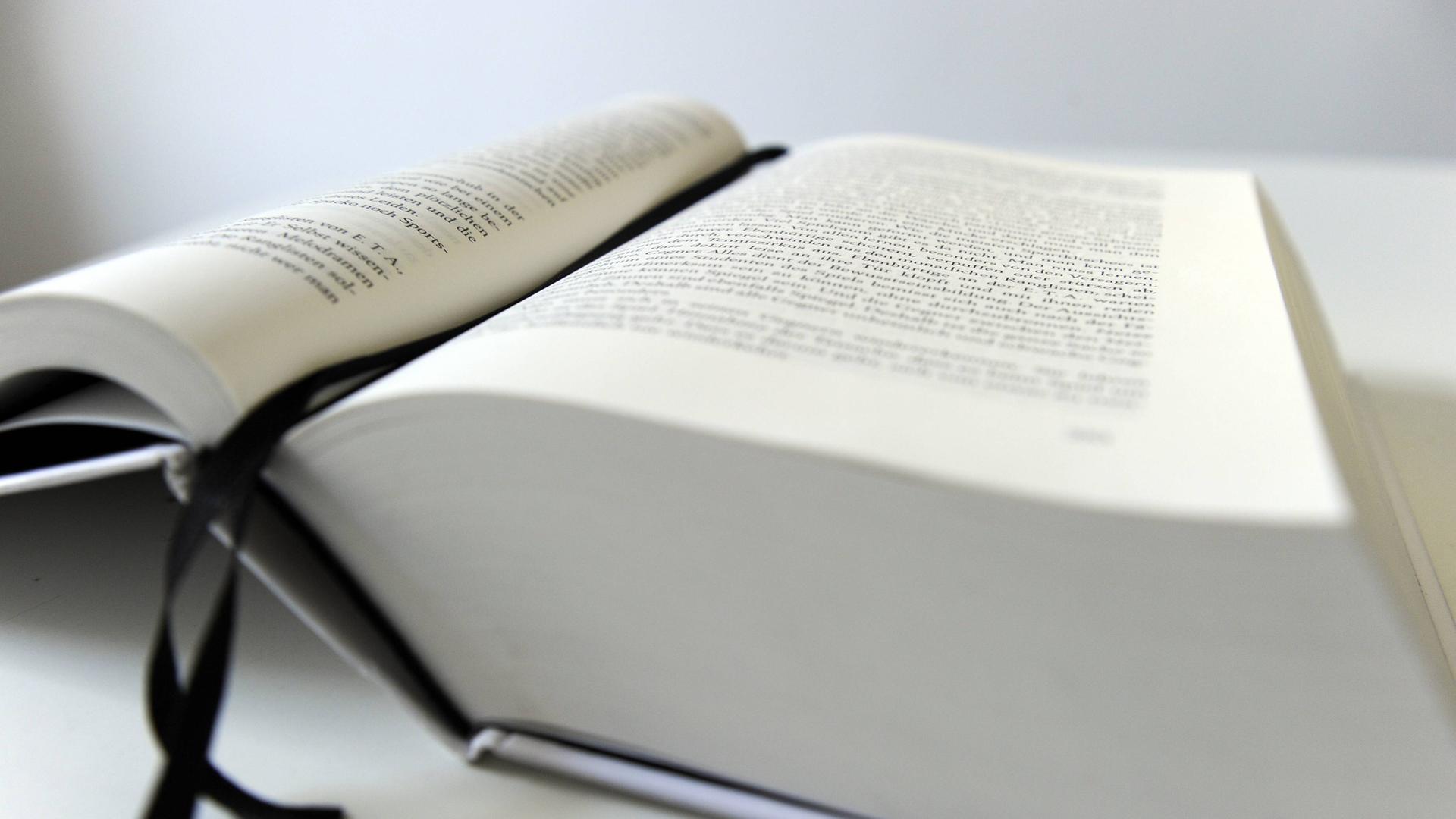 Ein dickes Buch liegt aufgeschlagen auf einem Tisch. Ein dickes Buch liegt aufgeschlagen auf einem Tisch.