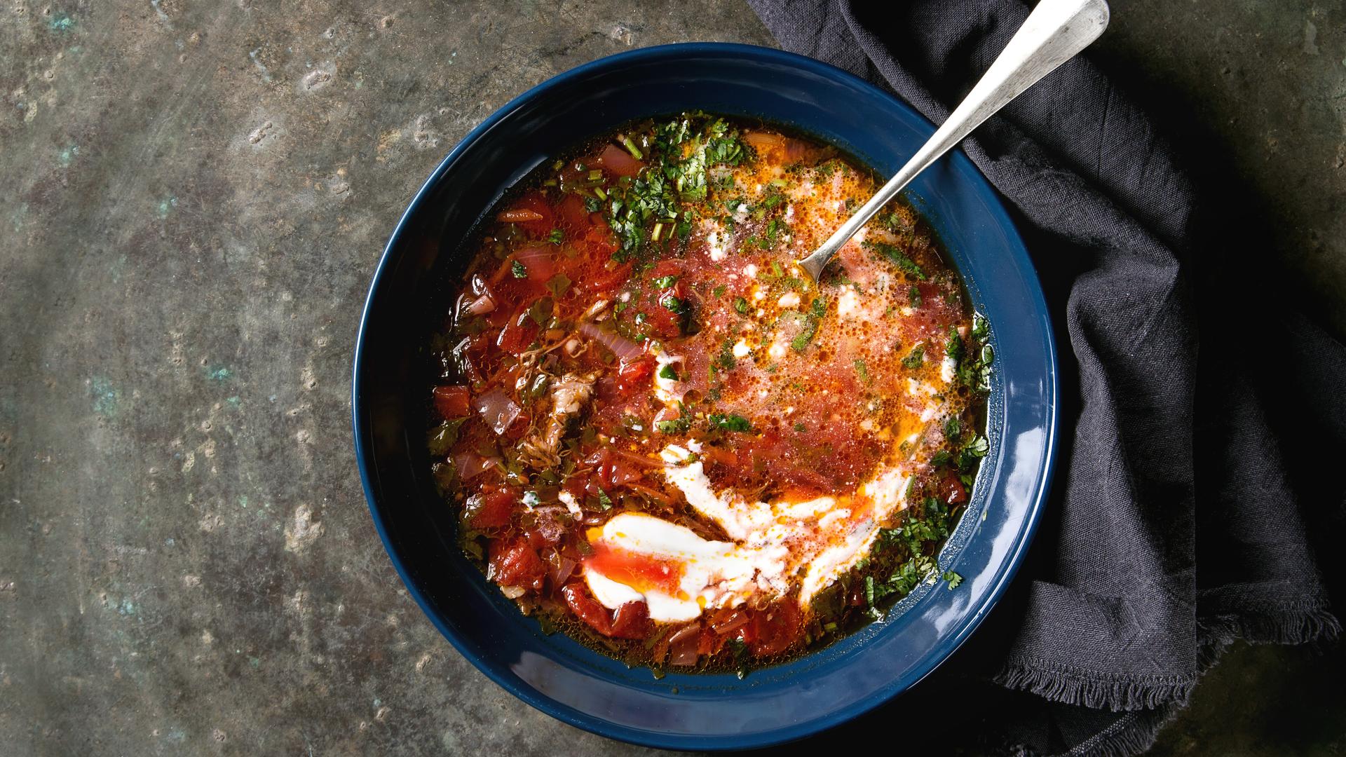 Eine Schüssel mit roter Suppe, Koriander und einem Klecks Sauercreme.