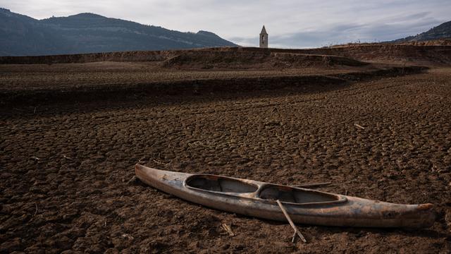 Ein ausgetrockneter Stausee in Katalonien: Im Vordergrund liegt ein Boot auf ausgetrockneter Erde, im Hintergrund sieht man einen Kirchturm