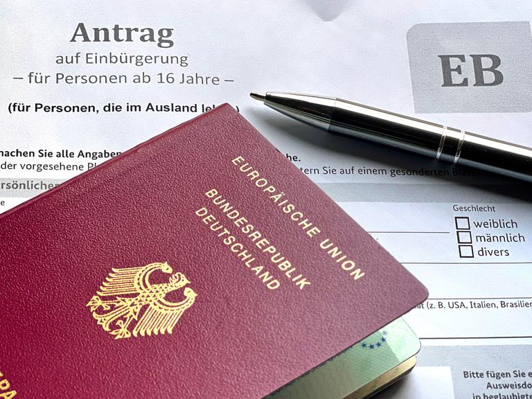 Ein Antrag auf Einbürgerung und ein deutscher Pass liegen auf einem Tisch.