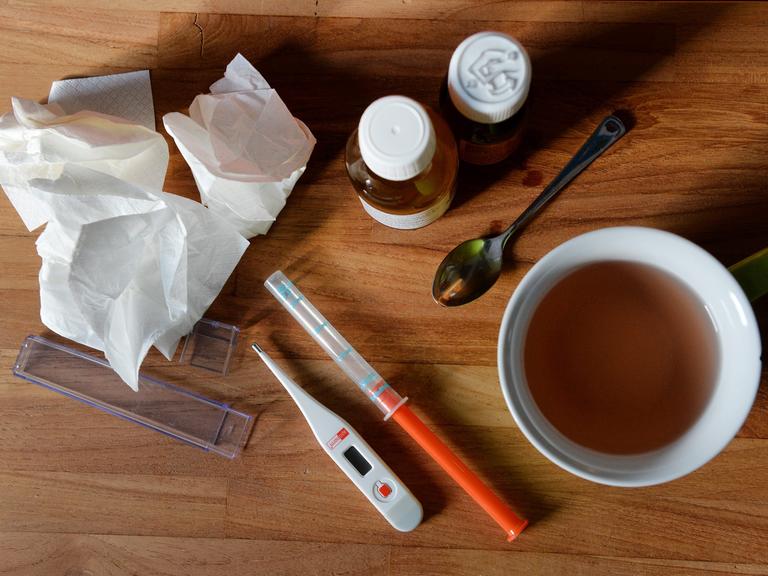 Auf dem Nachttisch eines kranken Jungen befinden sich Medikamente, Taschentücher und ein Fieberthermometer