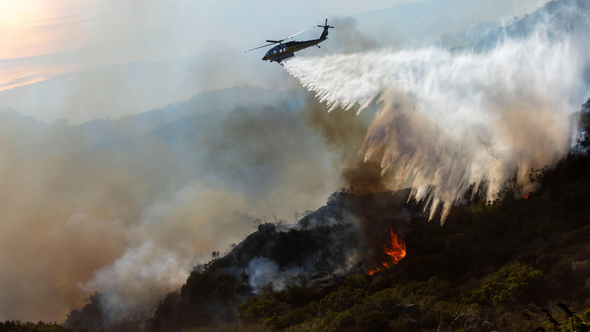 Ein Löschhubschrauber des Los Angeles County wirft Wasser auf das Franklin Fire, um Häuser an der nahe gelegenen Costa Del Sol in Malibu zu schützen. Ein Löschhubschrauber des Los Angeles County wirft Wasser auf das Franklin Fire, um Häuser an der nahe gelegenen Costa Del Sol in Malibu zu schützen.
