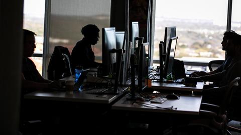 Conent-Moderatoren sitzen in einem Büro an ihren Schreibtischen und schauen auf Bildschirme.