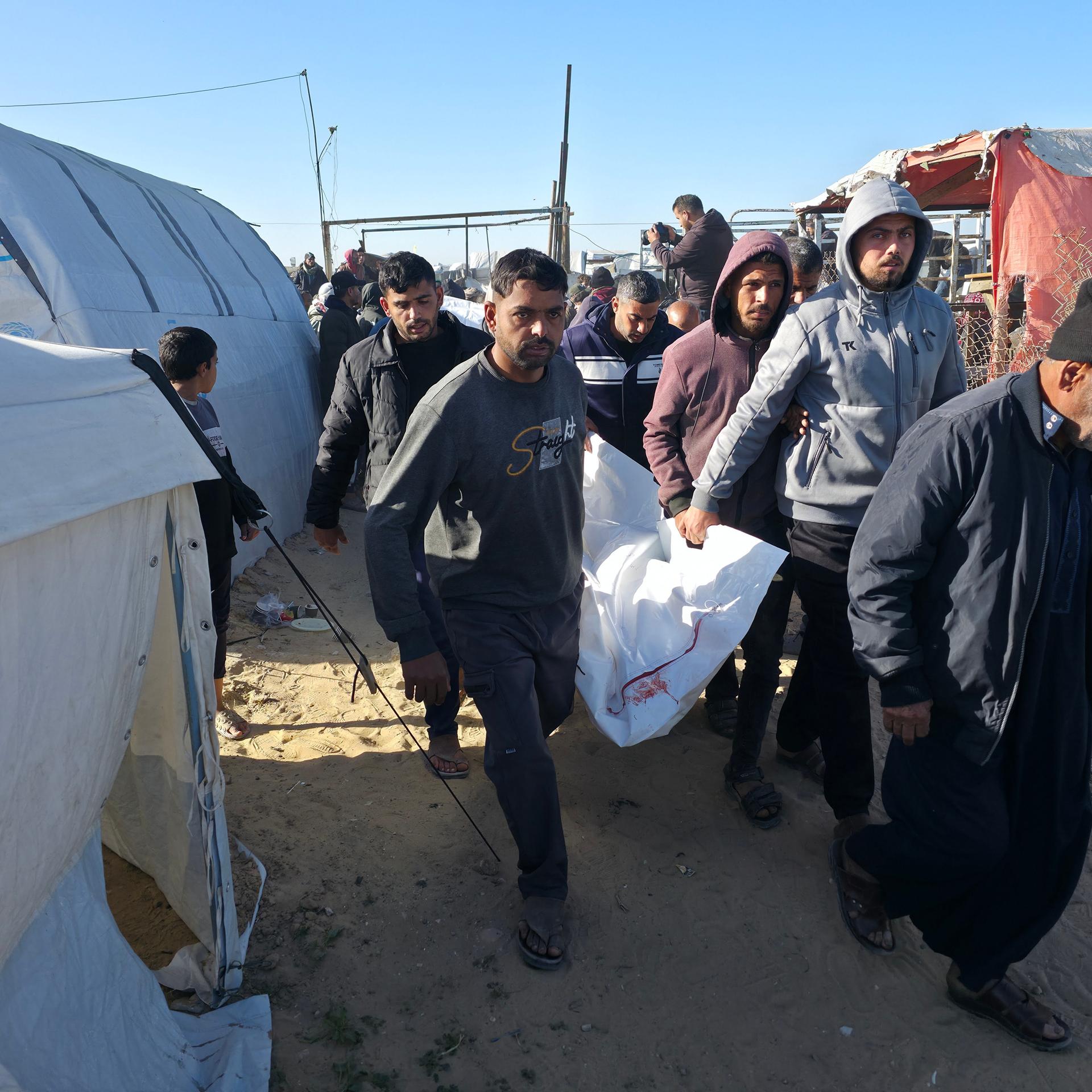 Männer tragen einen Leichensack durch die Zeltreihen in Chan Junis