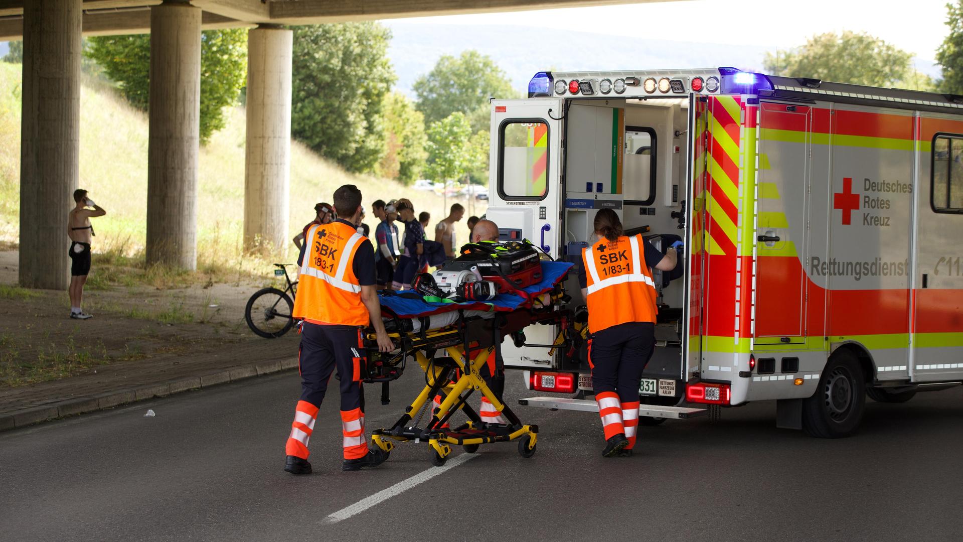 Einsatzkräfte vom Deutschen Roten Kreuz stehen an einer Trage hinter einem Rettungsfahrzeug. Einsatzkräfte vom Deutschen Roten Kreuz stehen an einer Trage hinter einem Rettungsfahrzeug.