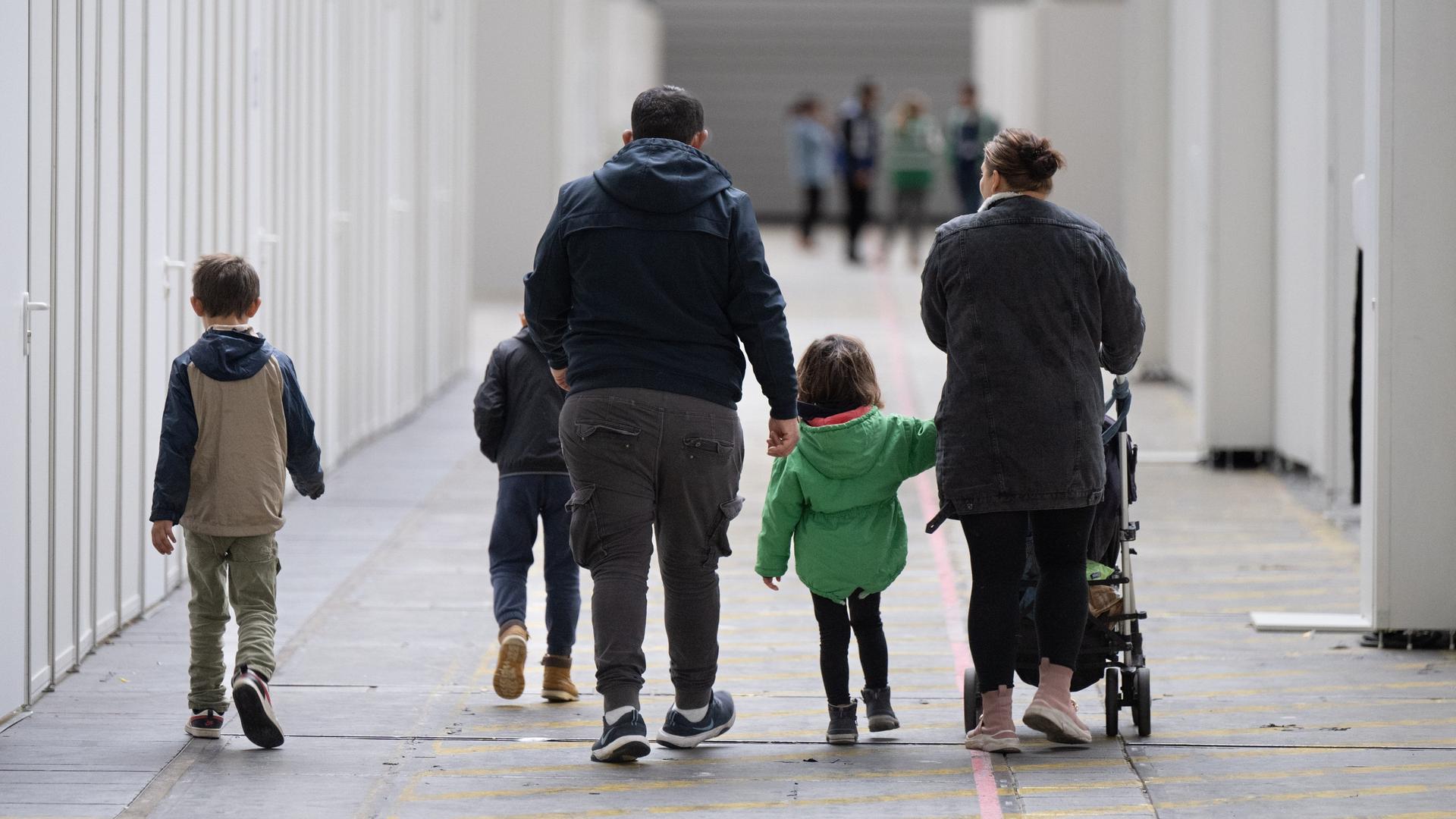 Eine Flüchtlingsfamilie geht durch eine zu einer Massenunterkunft umfunktionierten Messehalle in Frankfurt. In der Halle sind seit einigen Wochen mehrere hundert Migranten und Asylsuchende aus unterschiedlichen Herkunftsländern untergebracht.