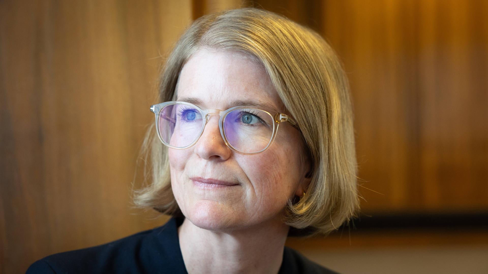 Porträt von Susanne Schwarzbach, aufgenommen im Funkhaus am Hans-Rosenthal-Platz. Sie trägt eine Brille mit hellem Rahmen, ein dunkles Oberteil und schaut leicht lächelnd zur Seite. Porträt von Susanne Schwarzbach, aufgenommen im Funkhaus am Hans-Rosenthal-Platz. Sie trägt eine Brille mit hellem Rahmen, ein dunkles Oberteil und schaut leicht lächelnd zur Seite.