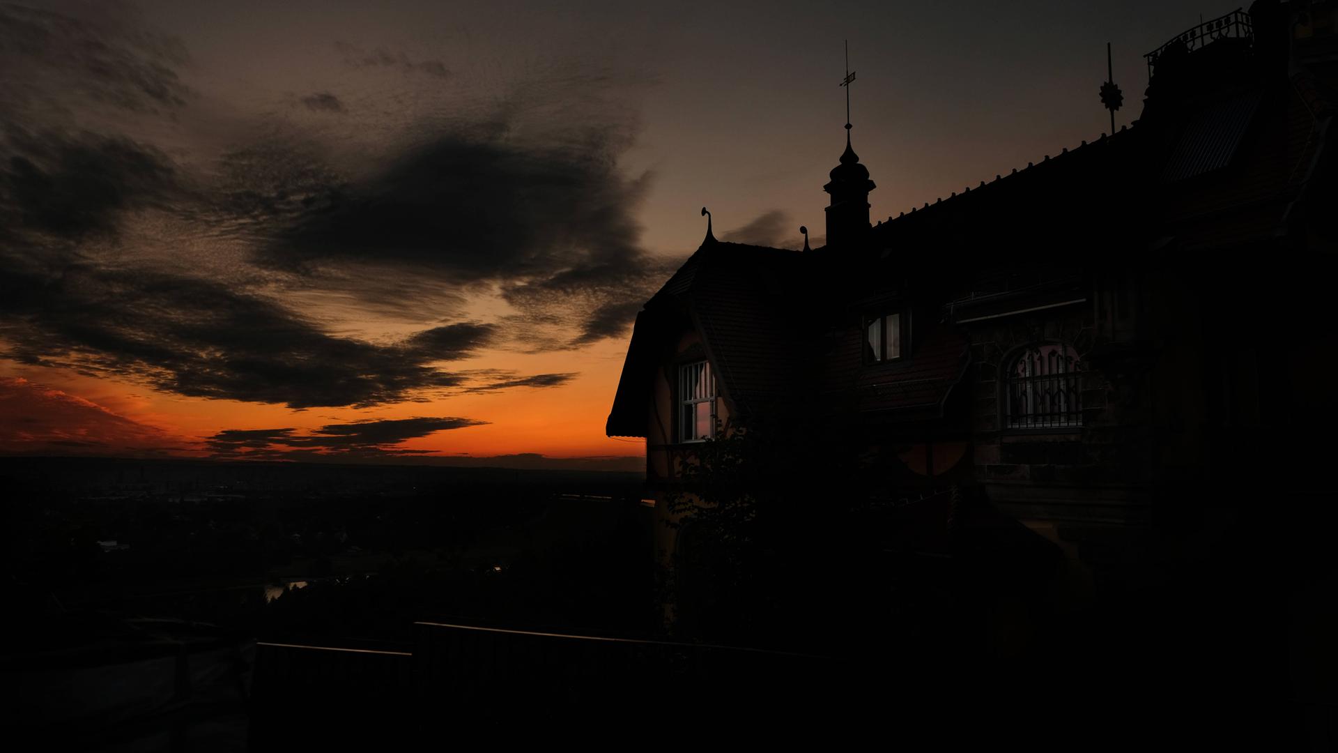 Zu sehen: Die Umrisse der Villa Steinstraße 17 in Dresden-Oberloschwitz, eine dunkle Silhouette vor einem blutroten Sonnenuntergang.