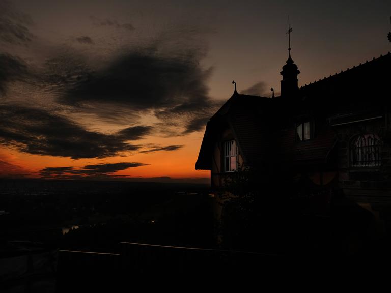 Zu sehen: Die Umrisse der Villa Steinstraße 17 in Dresden-Oberloschwitz, eine dunkle Silhouette vor einem blutroten Sonnenuntergang.