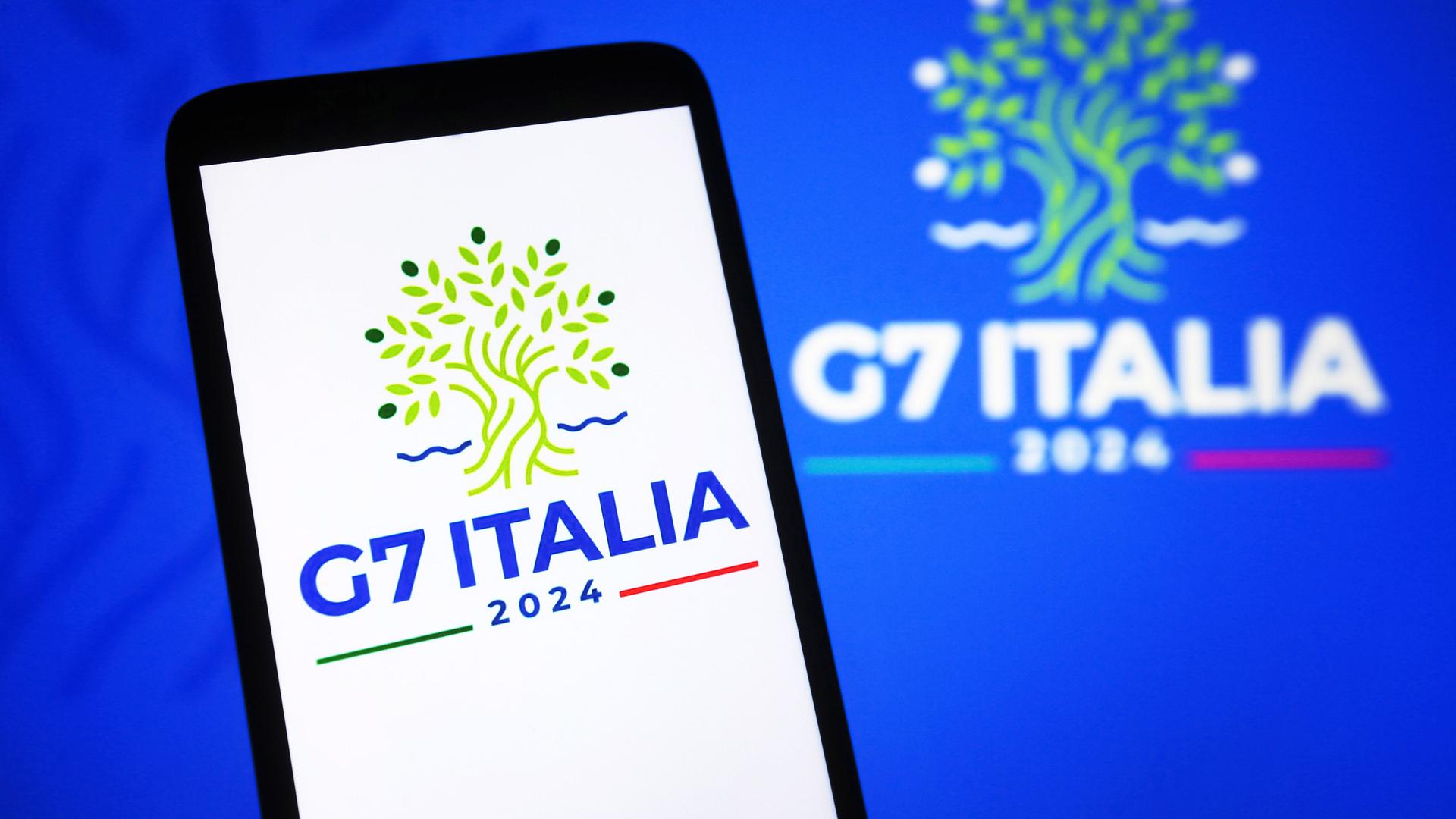 Das Logo des G7-Treffens in Italien ist auf einem Handy zu sehen. 