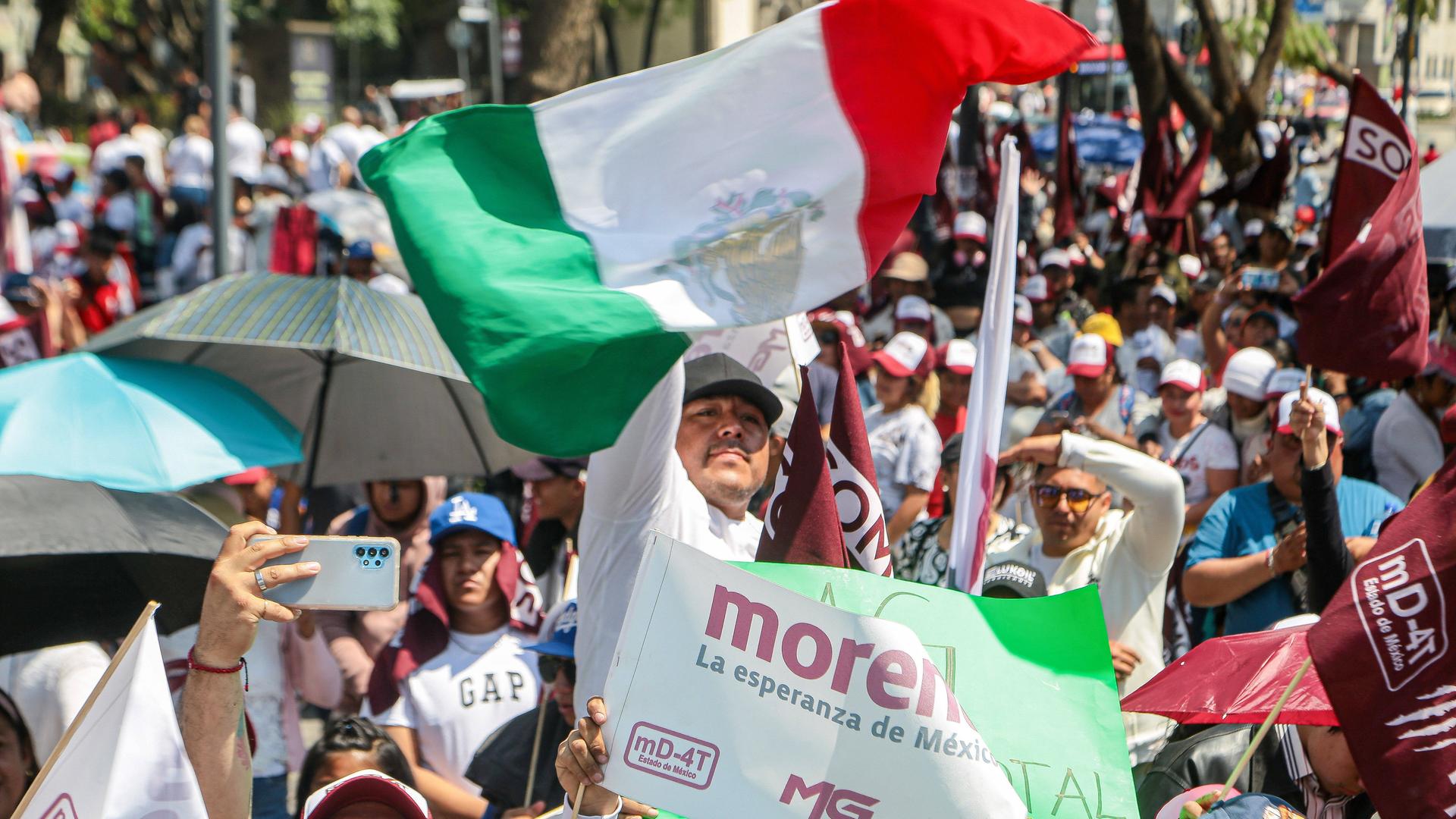 Ein Unterschützer der mexikanischen Präsidentschaftskanidatin Claudia Sheinbaum hält während einer Kundgebung in Mexiko City eine mexikanische Fahne in die Höhe.