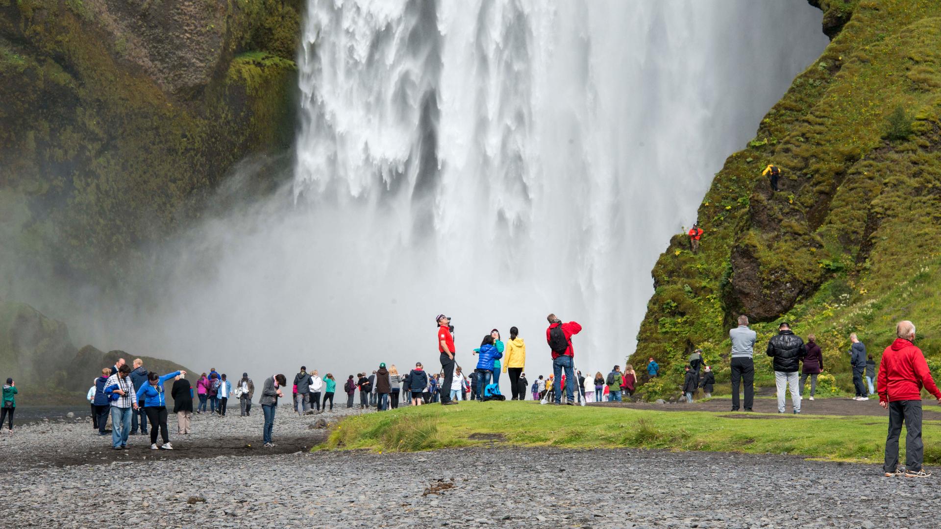 Touristengruppen stehen vor einem riesigen Wasserfall.