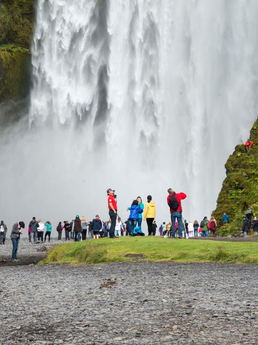 Touristengruppen stehen vor einem riesigen Wasserfall.