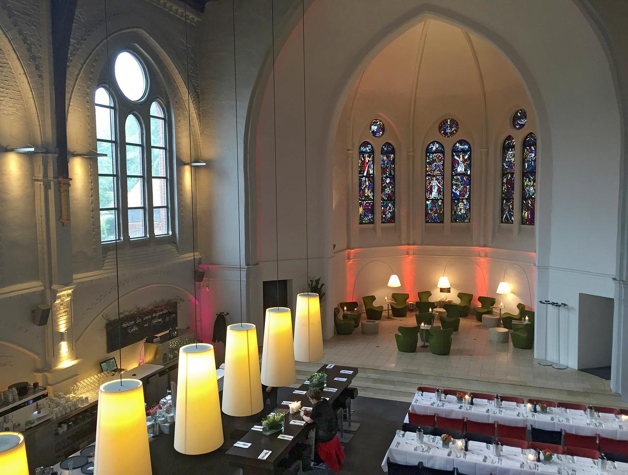 Blick in eine ehemalige Kirche mit Restauranttischen und Stühlen.