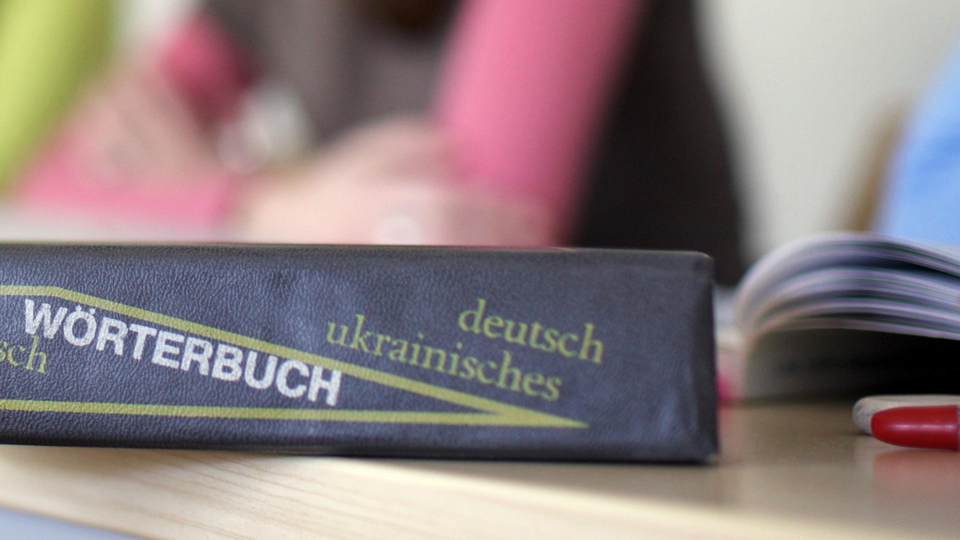 Ein Wörterbuch der deutschen und ukrainischen Sprache liegt auf einem Tisch 