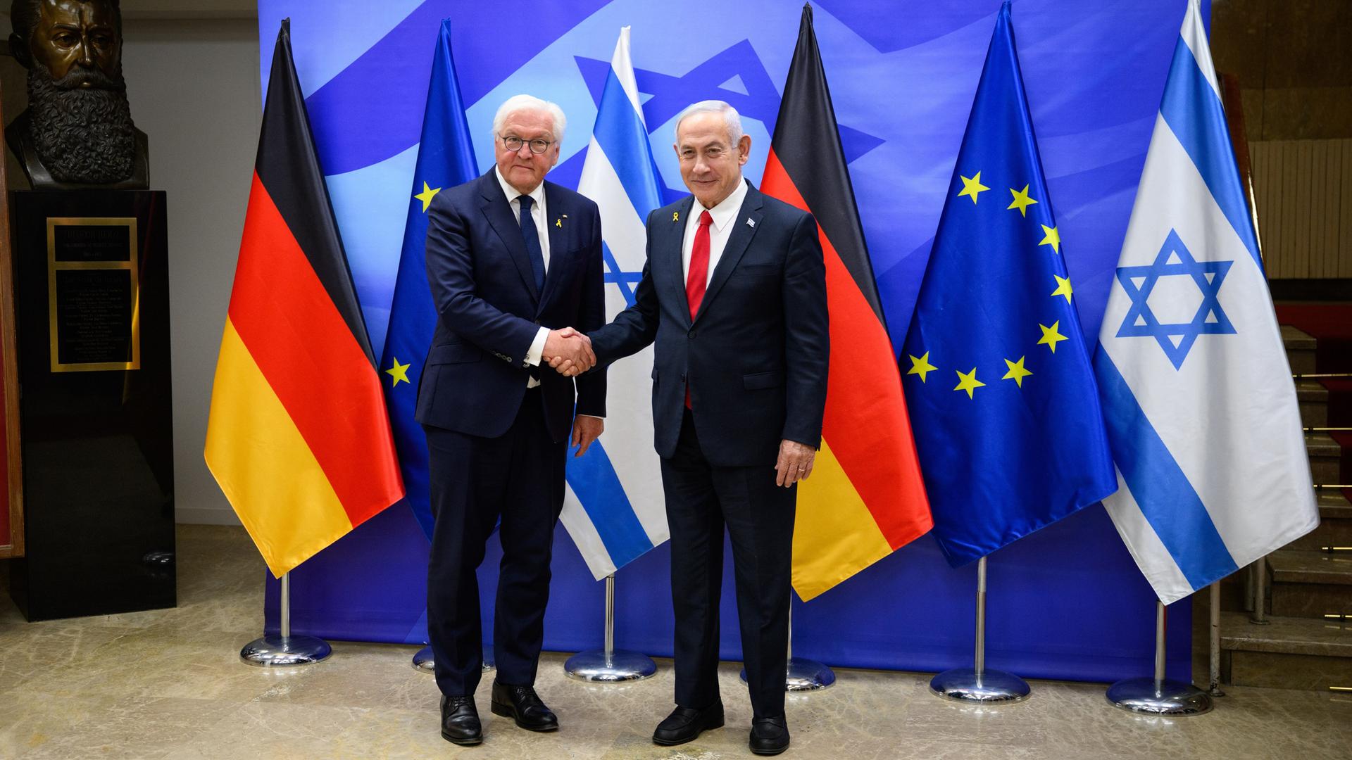 Bundespräsident Frank-Walter Steinmeier (l) und Benjamin Netanjahu, Ministerpräsident von Israel, treffen sich zu einem Gespräch im Amtssitz des Ministerpräsidenten. Beide stehen vor deutschen und israelischen Flaggen und schütteln sich die Hände.