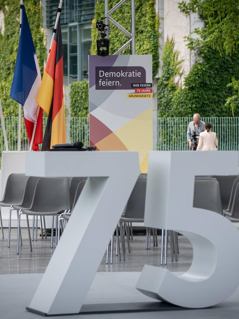 Beim Fest zum Jubiläum des Grundgesetzes steht eine große graue 75 vor einem Plakat "Demokratie feiern".