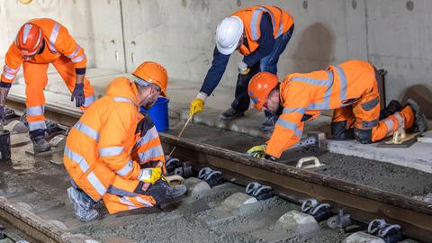 Arbeiter in orangen Warnwesten arbeiten gemeinsam an einem Gleisabschnitt. Arbeiter in orangen Warnwesten arbeiten gemeinsam an einem Gleisabschnitt.