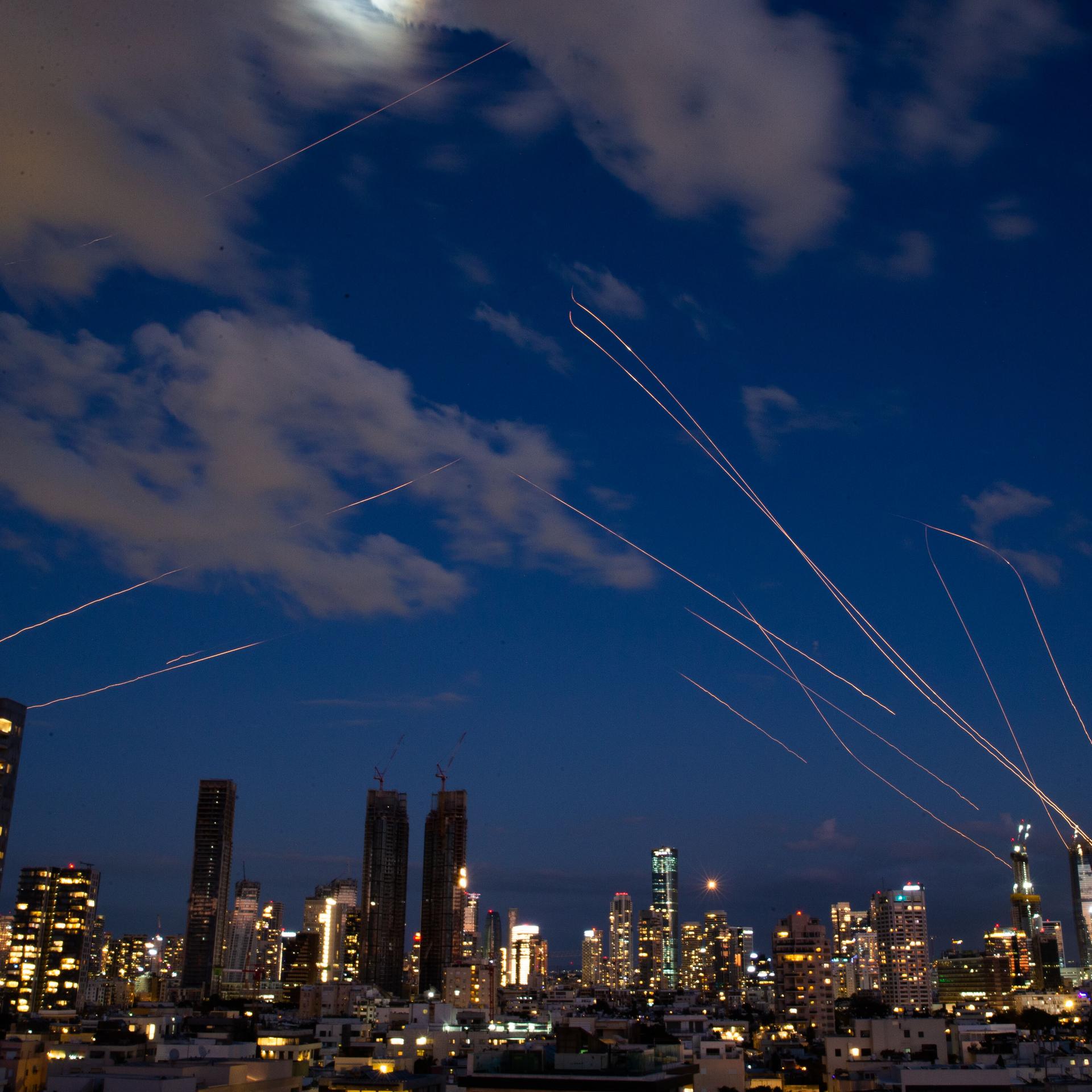 Diese Langzeitbelichtung zeigt die Skyline von Tel Aviv bei Nacht mit Leuchtspuren von Abfangraketen, die von israelischen Luftverteidigungssystemen in Tel Aviv abgefeuert wurden.