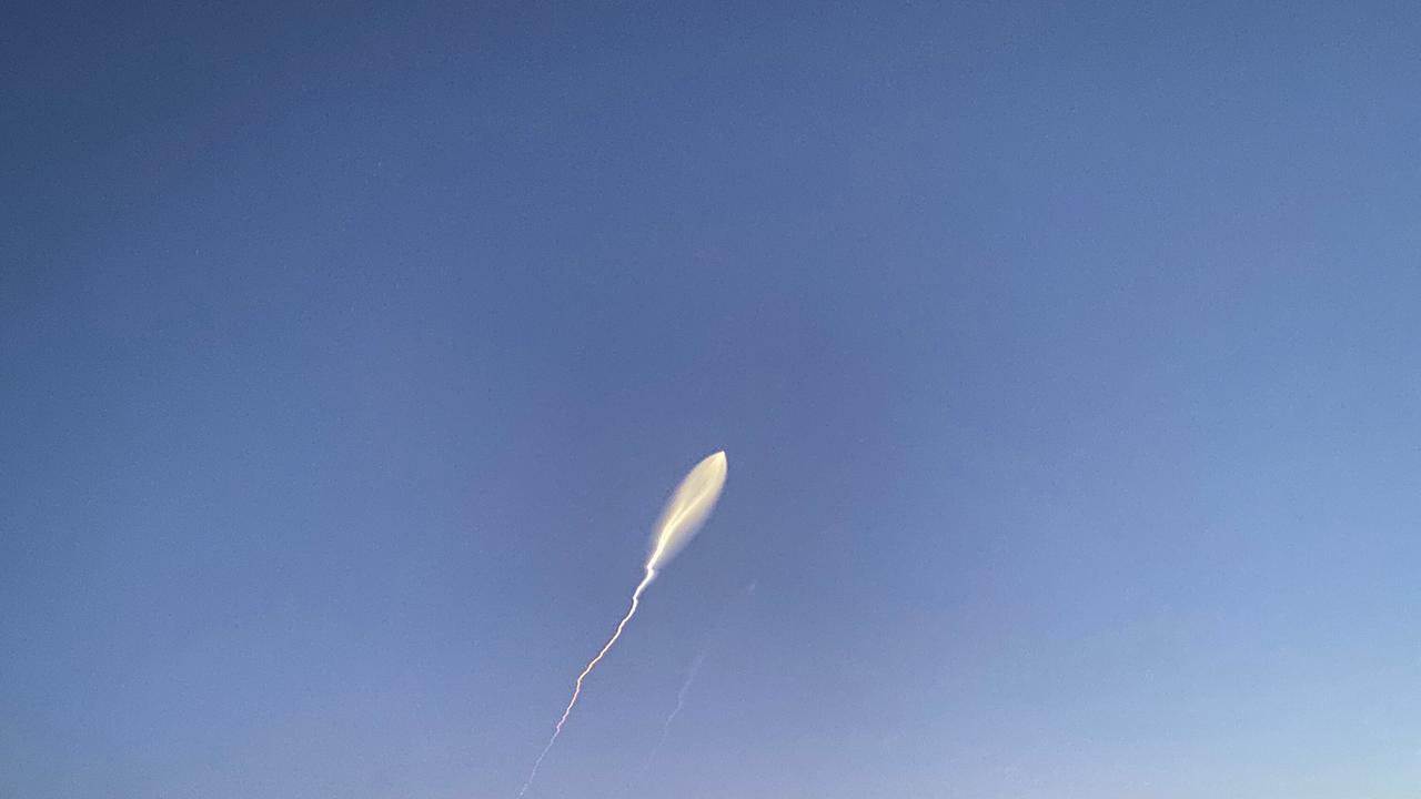 Am blauen Himmel fliegt eine Rakete. Sie hinterlässt einen weißen Schleier.