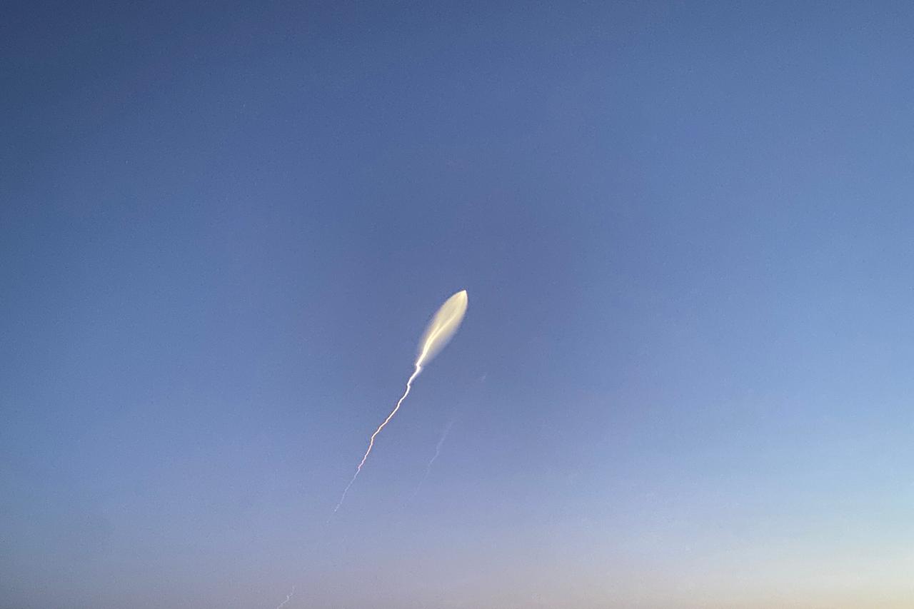 Am blauen Himmel fliegt eine Rakete. Sie hinterlässt einen weißen Schleier.