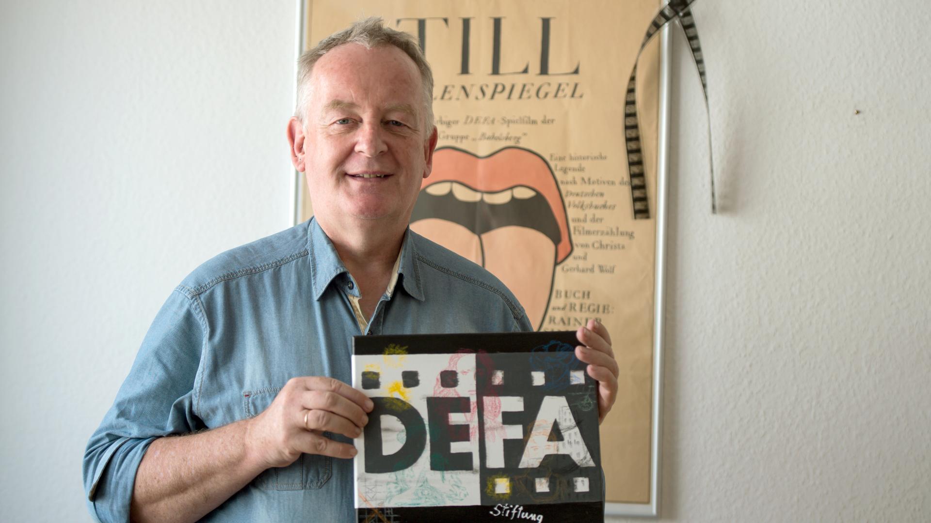 Ralf Schenk in seinem Büro mit einem Schild mit der Aufschrift "DEFA"