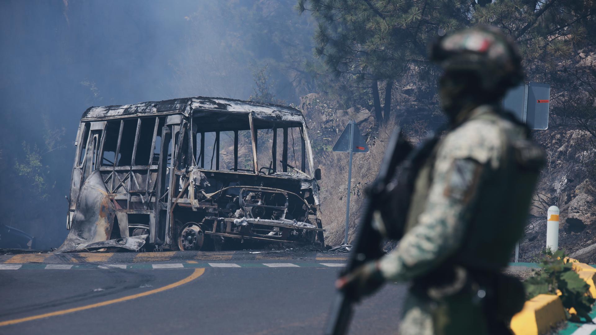 Ein Soldat steht in Cointzio neben einem ausgebrannten Bus. Ein Soldat steht in Cointzio neben einem ausgebrannten Bus.