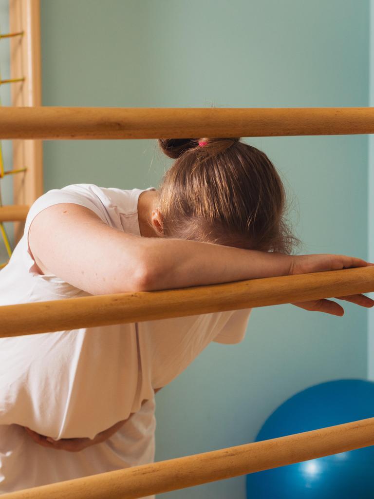 Eine schwangere Frau lehnt in einem Kreißsaal an einer Sprossenwand und stützt den Kopf vor Schmerzen auf den Arm. (Symbolbild) Eine schwangere Frau lehnt in einem Kreißsaal an einer Sprossenwand und stützt den Kopf vor Schmerzen auf den Arm. (Symbolbild)