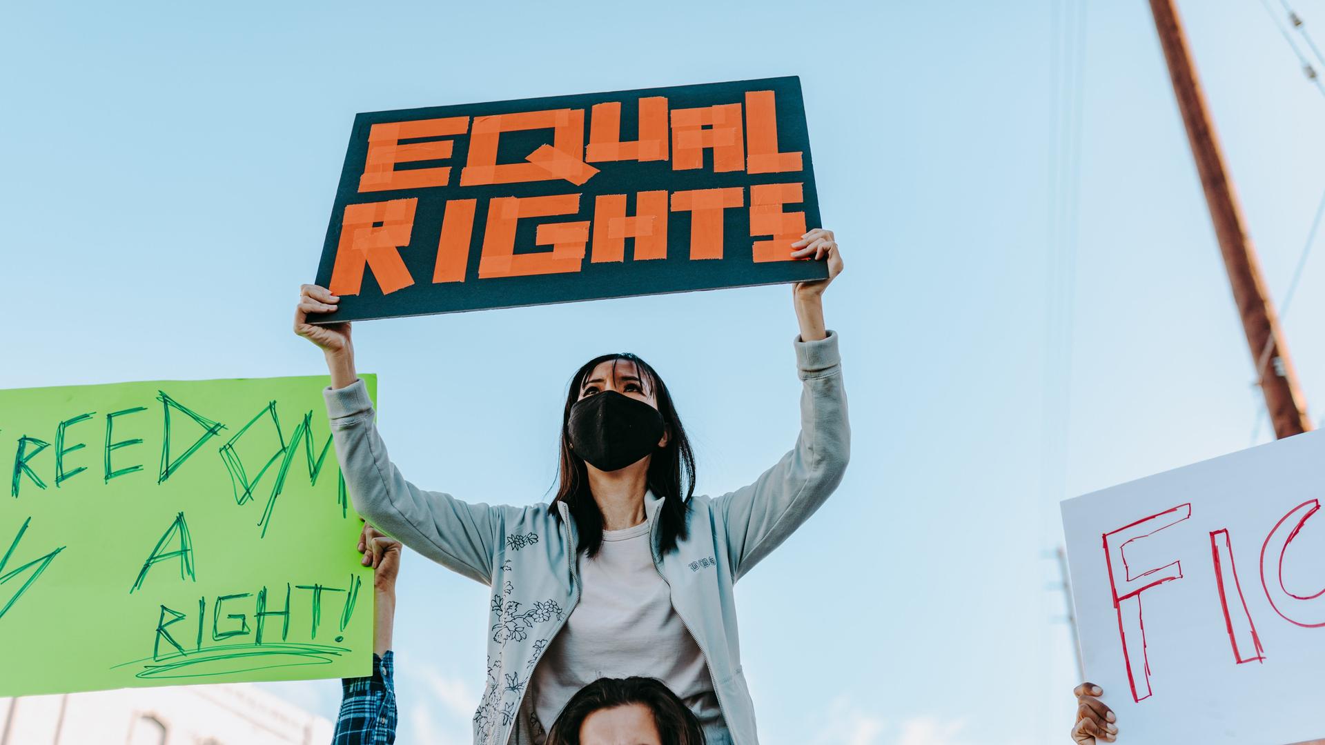 Eine Frau hält ein Schild hoch auf dem "Equal Rights" steht.
