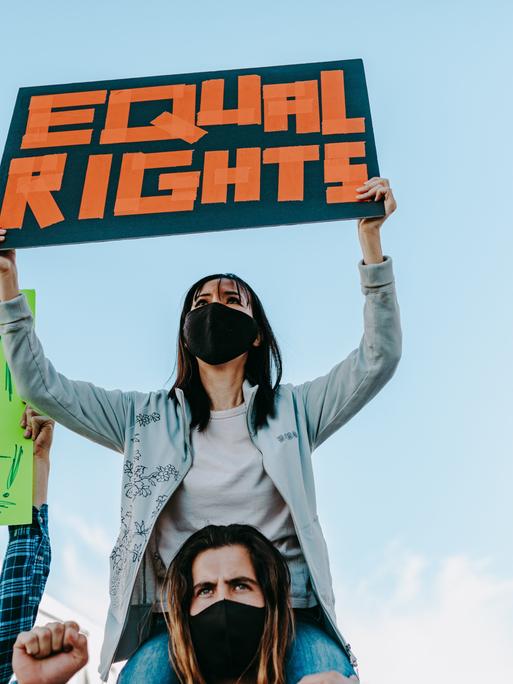 Eine Frau hält ein Schild hoch auf dem "Equal Rights" steht.