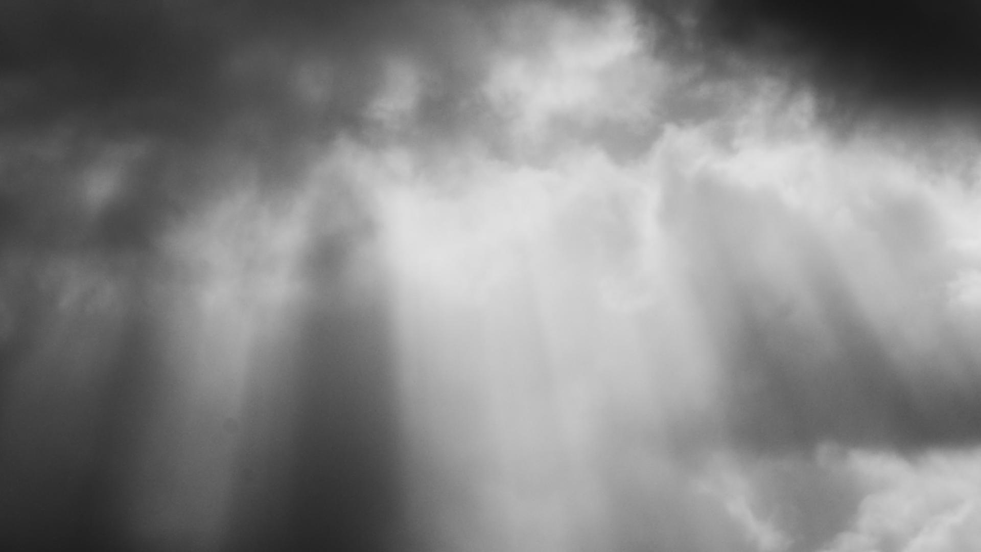 Dunkle Wolken und Sonnenstrahlen und schwarz-weiß.
