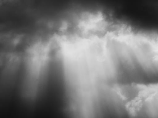 Dunkle Wolken und Sonnenstrahlen und schwarz-weiß.