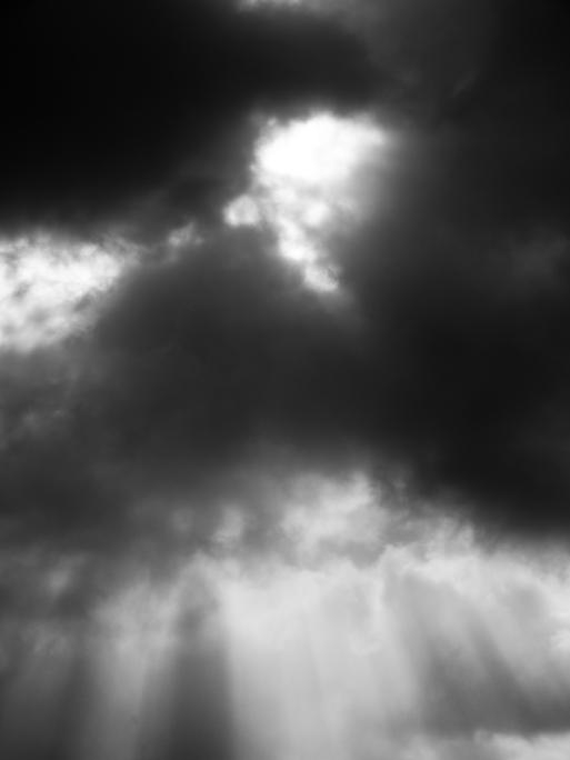 Dunkle Wolken und Sonnenstrahlen und schwarz-weiß.
