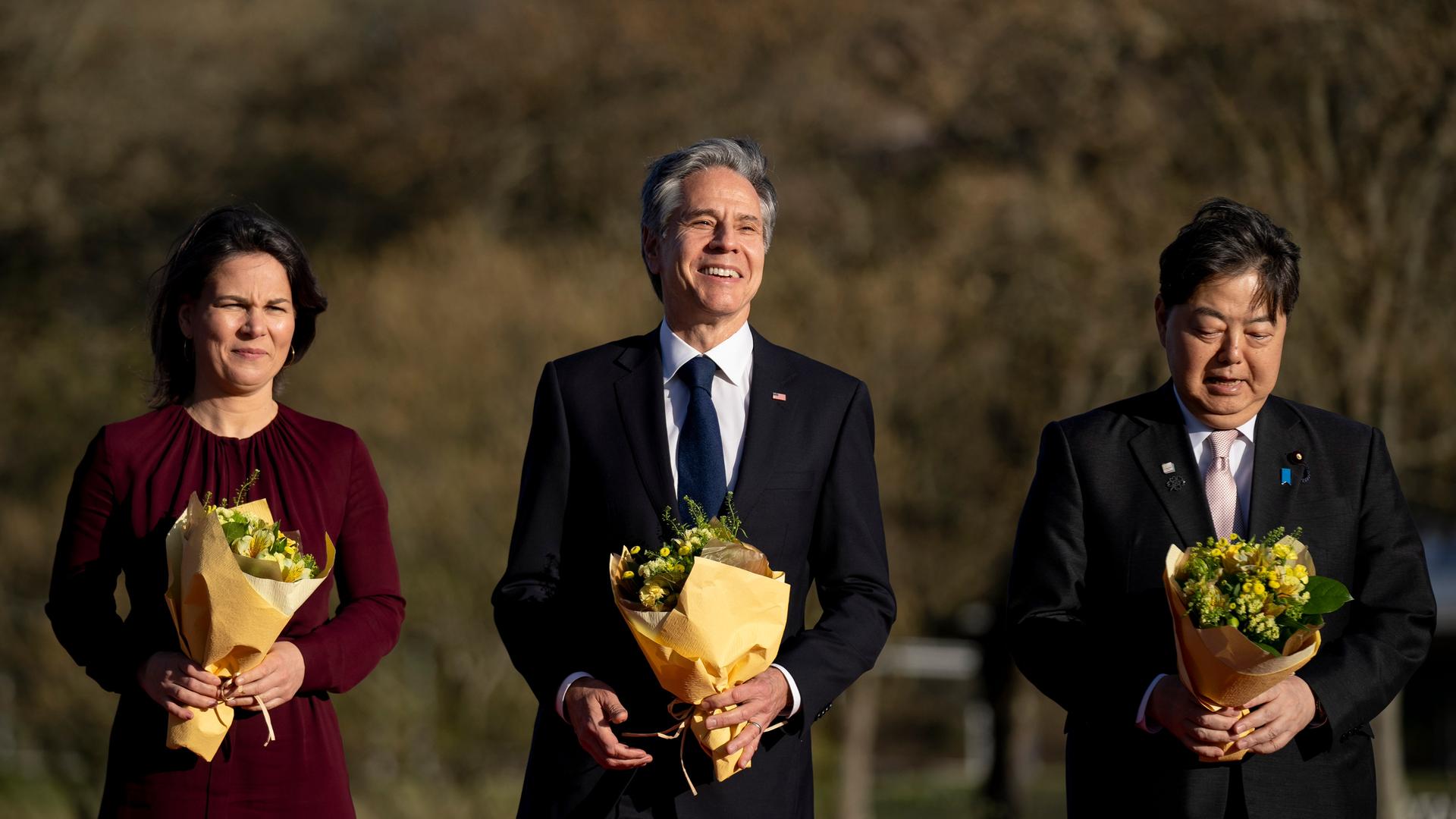 Bundesaußenministerin Baerbock, US-Außenminister Blinken und Japans Außenminister Hayashi mit Blumensträußen beim Fototermin