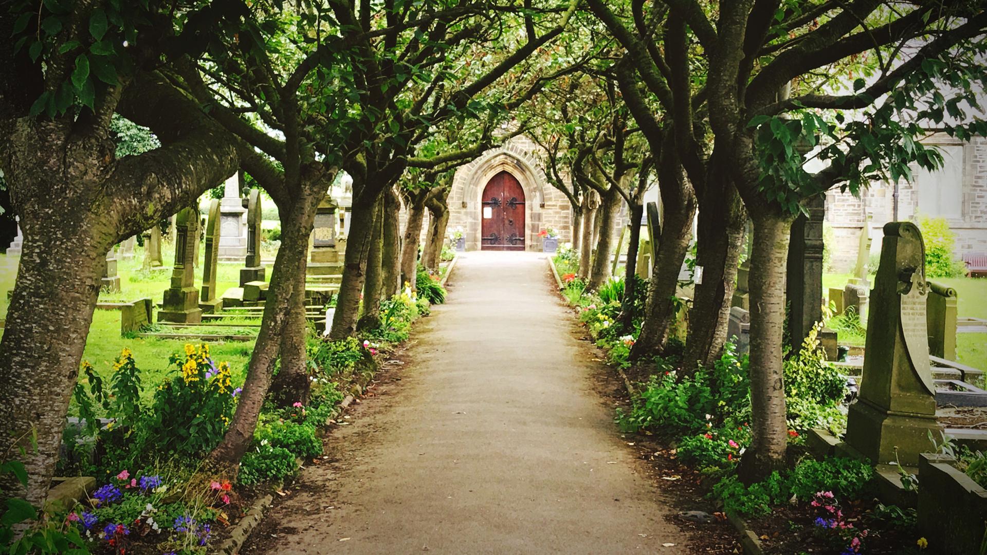 Arbeiten auf einem Friedhof - Einblicke in Abschied und Trauer. Zu sehen: Auf einem Friedhof ein Weg zur Kapelle. 