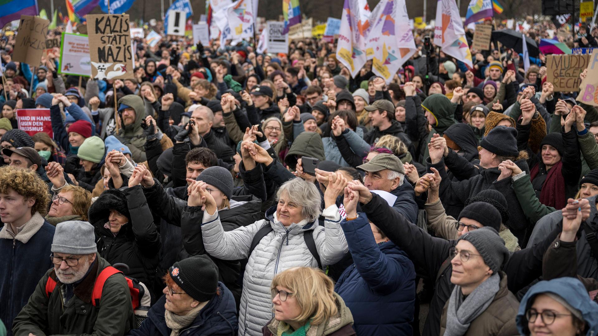 Teilnehmer einer Demonstration unter dem Motto "Aktionstag Hand in Hand - Wir Sind Die Brandmauer gegen Rechtsextremismus" stehen auf der Reichstagswiese vor dem Bundestag am 03.02.2024 in Berlin und fassen sich an den Händen.