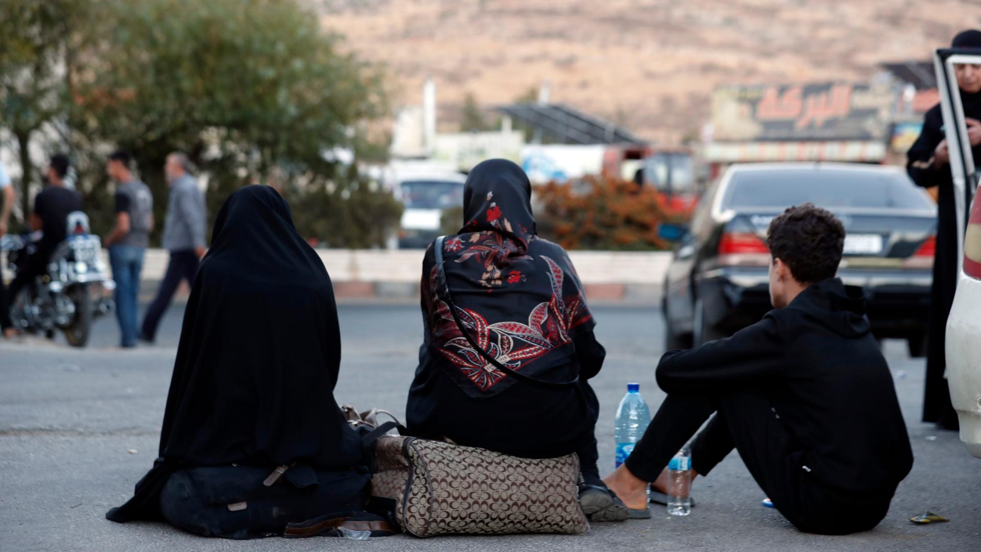 Libanesen, die vor dem israelischen Bombardement fliehen, sitzen auf dem Boden, nachdem sie den syrisch-libanesischen Grenzübergang in Jdaidet Yabous überquert haben.