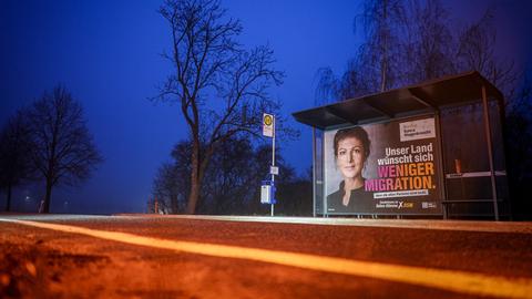 Ein Wahlplakat mit Sahra Wagenknecht, Prarteivorsitzende vom BSW und Bundestagsabgeordnete, ist am frühen Morgen an einer Bushaltestelle zu sehen. Auf dem Plakat ist zu lesen "Unser Land wünscht sich weniger Migration".