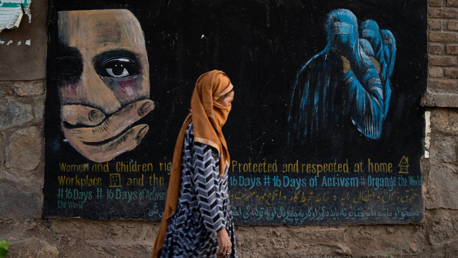 Eine verschleierte Frau geht an einem Wandgemäldein Bamian, Afghanistan vorbei, das die Rechte von Frauen und Kindern in Afghanistan einfordert. Der Zusammenbruch der Wirtschaft und das Einfrieren der Gelder der Afghanen und der Geber nach der Übernahme des Landes durch die Taliban im August 2021 haben eine humanitäre Krise ausgelöst. Die meisten Kunst-, Kultur- und Freizeitaktivitäten wurden verboten. Auch die weibliche Bevölkerung musste ihre Arbeit aufgeben, und junge Mädchen nach dem 12. Lebensjahr können nicht mehr zur Schule gehen oder eine weiterführende Ausbildung absolvieren.