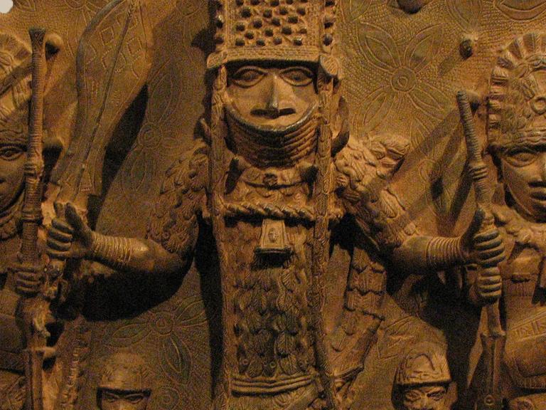 Auf einem Bronzerelief aus Benin sind Krieger mit Speeren, Rüstung und Helmen abgebildet. 