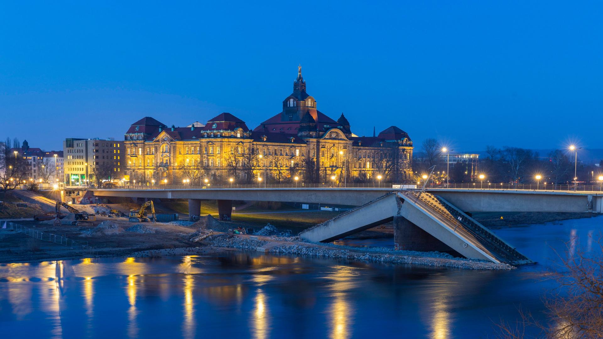 Im Vordergrund ist der eingestürzte Teil der Carolabrücke in Dresden zu sehen. Dahinter der noch stehende Teil mit der Stadtsilhouette. 