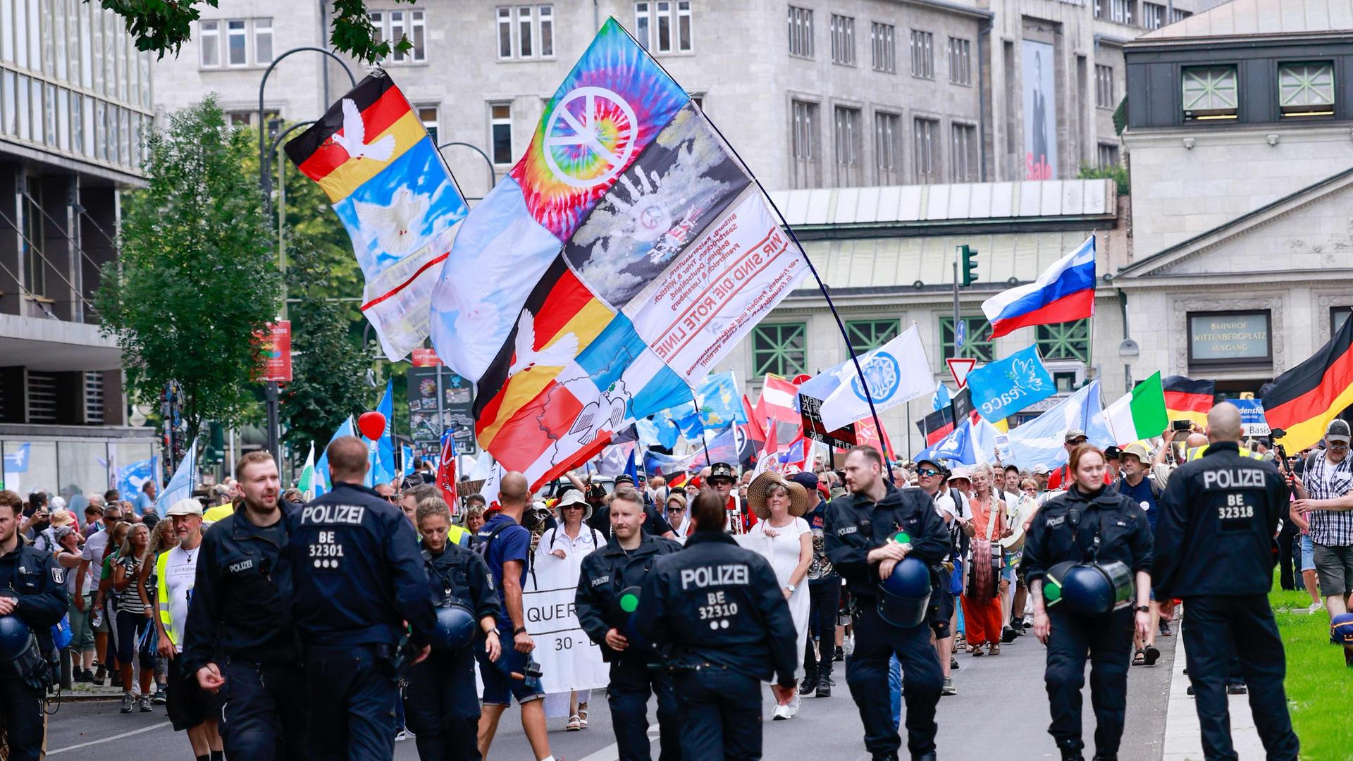 Das Foto zeigt Unterstützer der Demonstration der sogenannten Querdenkerbewegung "Einigkeit und Recht und Freiheit - der Umzug". Sie schwenken Deutschland - und Friedensbewegungfahnen. 