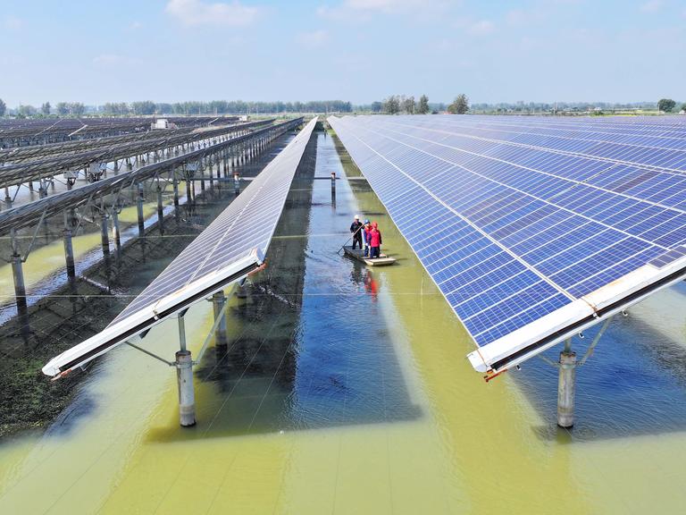 Solarmodule sind in langen Reihen über einem See installiert. Solarmodule sind in langen Reihen über einem See installiert.