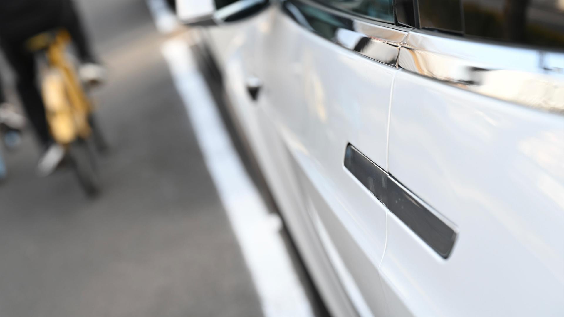 Peking: Menschen fahren an einem Elektroauto vorbei, an dem ein versenkbarer Türgriff angebracht ist.