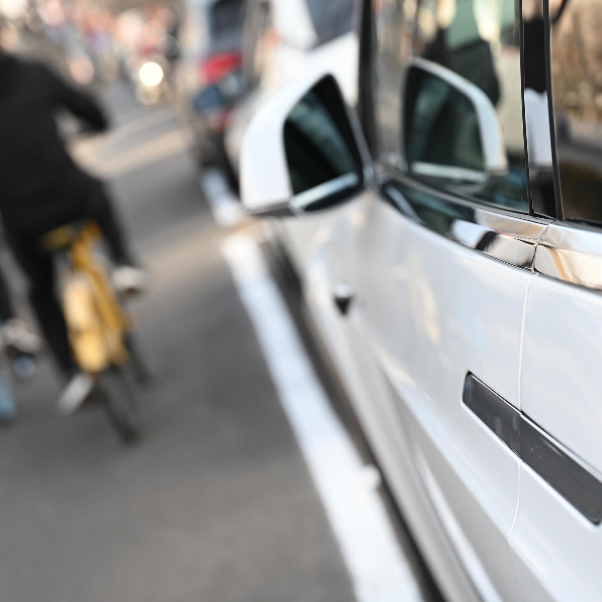 Peking: Menschen fahren an einem Elektroauto vorbei, an dem ein versenkbarer Türgriff angebracht ist.