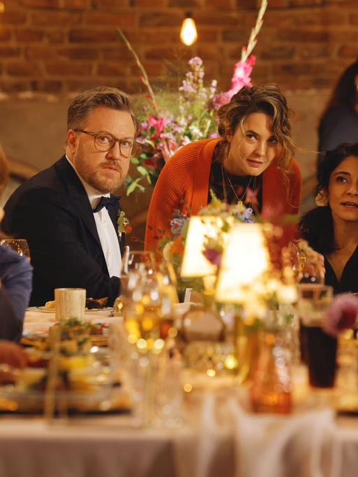 Filmszene aus Feste Freunde. Zu sehen sind Tom Trambow, Natalie (Jasmin Shakeri) und Maya (Katia Fellin) mit den Frischvermählten Rolf (Nicholas Ofczarek) und Dina (Pegah Ferydoni) an einer festlichen Tafel.