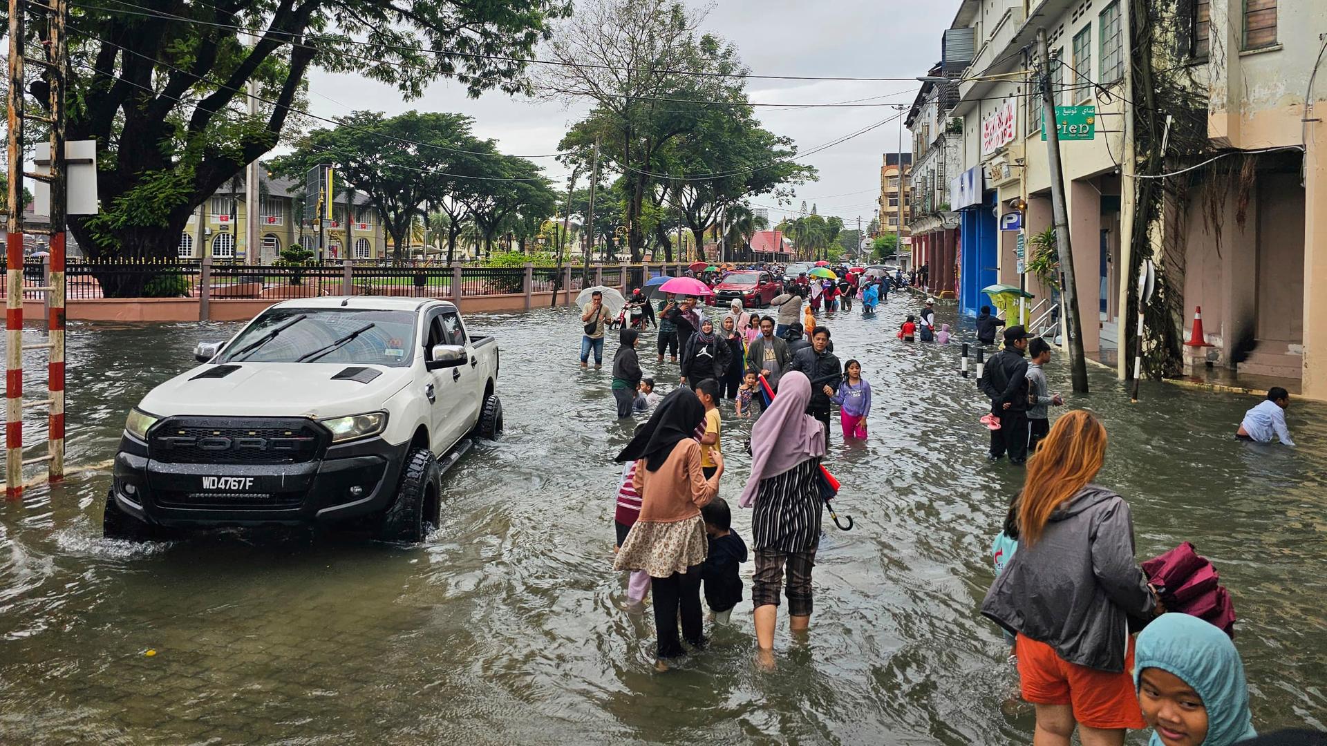 Menschen versuchen sich in Kota Bharu in der Provinz Ketalan in Malaysia durch eine überflutete Straße in Sicherheit zu bringen.